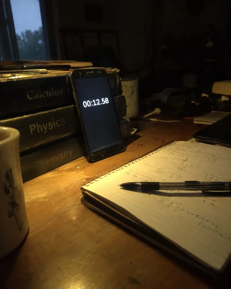 A phone propped against some books running a stopwatch at night