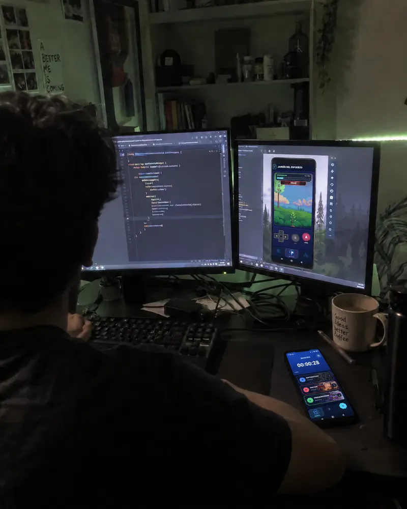 Two monitors, one with code and one with the Lock In garden, and a phone with a session running